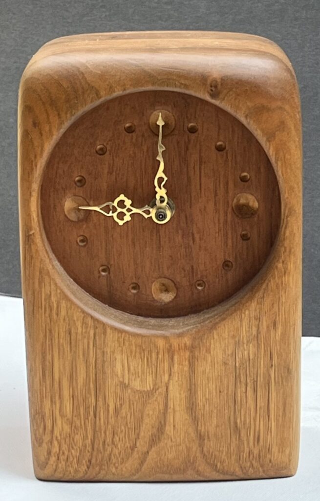 carved wood clock with gold hands at nine o'clock