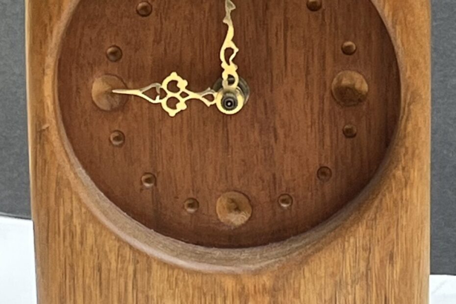 carved wood clock with gold hands at nine o'clock