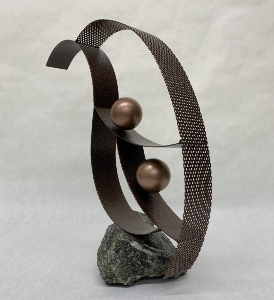 metal sculpture with curved steel strips with two steel spheres mounted on stone