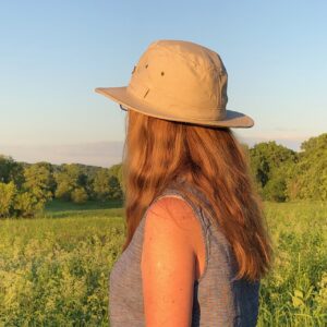 Woman wiith long hair, wearing straw hat facing away from camera