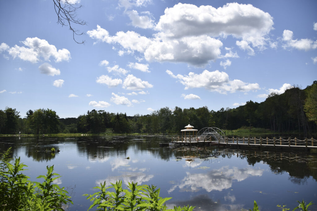 photo of calm lake blue sky and white clouds reflected long walkway into the lake